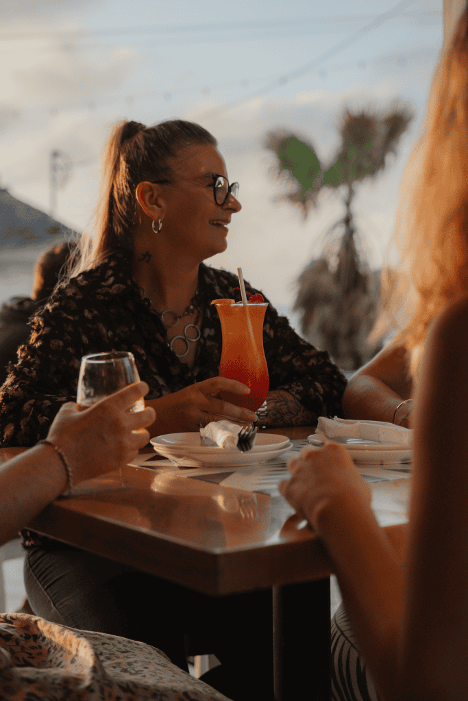 A woman enjoying a tropical cocktail at Bite Club Cayman, a hidden gem restaurant in the Cayman Isla.