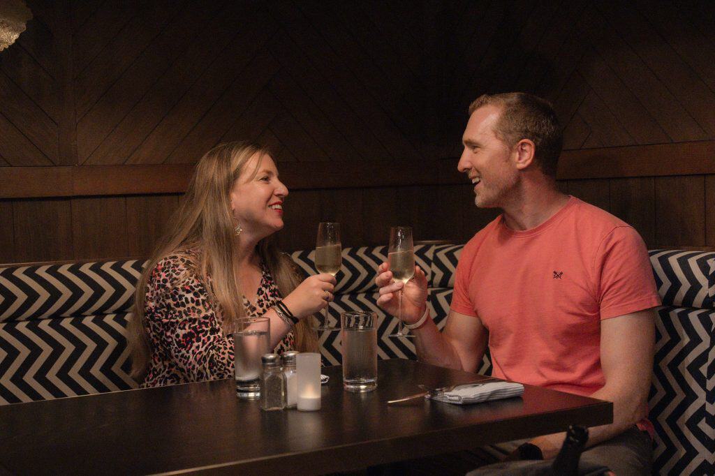 Couple toasting with champagne across a restaurant table during a romantic dinner in Grand Cayman.