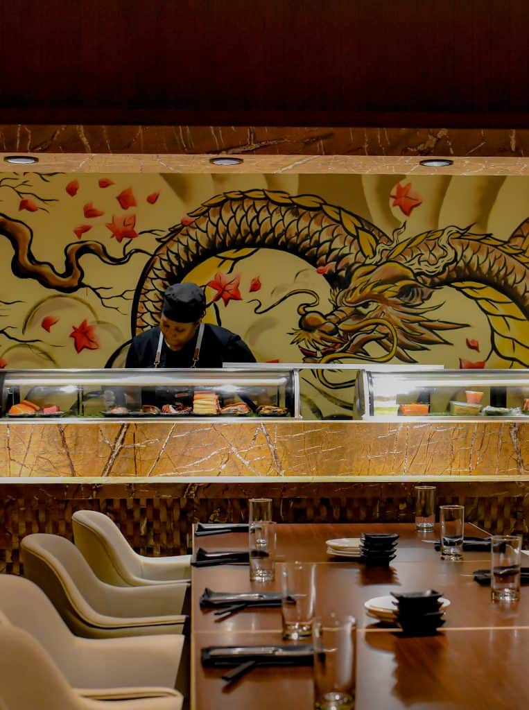 Sushi chef working behind sushi bar preparing food in Cayman restaurant